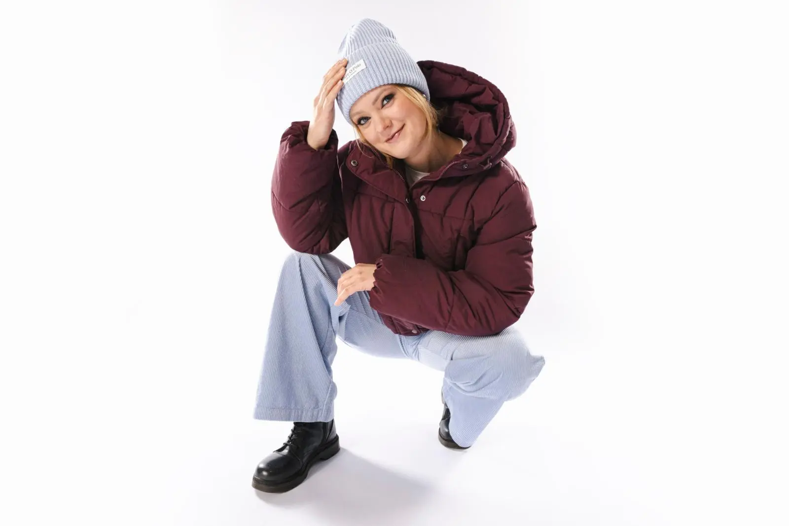 Mallilla päällä vaaleansininen pipo, viininpunainen toppatakki ja vaaleansiniset housut.