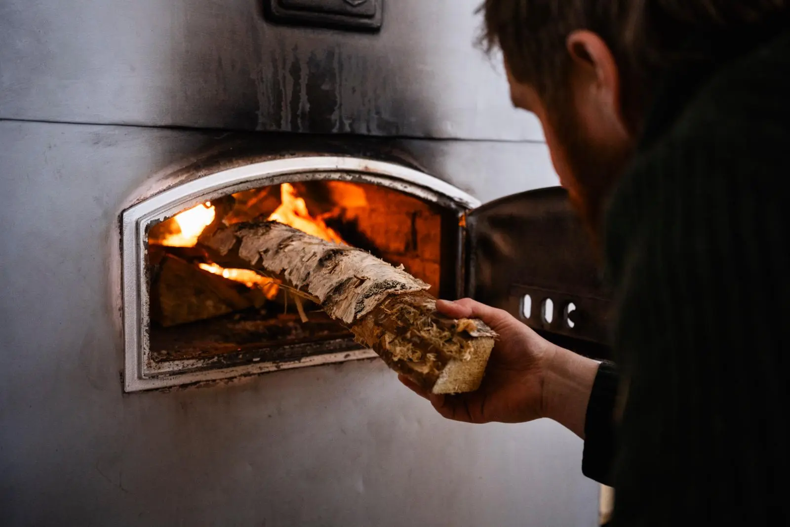 Tommi Manninen laittaa puita leivinuniin