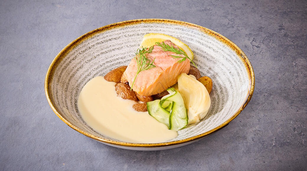 Annos lohta vaaleassa kermakastikkeessa, koristeltuna tillillä ja sitruunaviipaleella, kullanruskea-reunaisella lautasella.