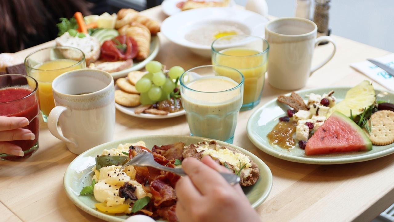 Värikäs aamiaispöytä täynnä Kiisan buffetin antimia: lautasilla lämpimiä ruokia, croissantteja ja hedelmiä, laseissa mehuja ja kupeissa kahvia