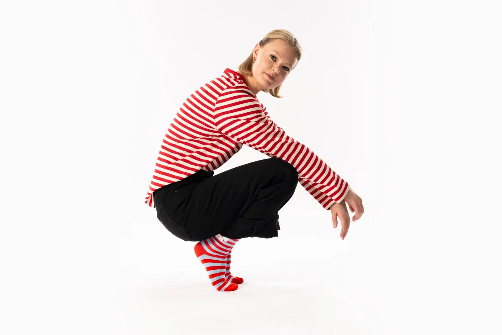 Mallin päällä puna-valkoinen raitapaita, mustat farkut ja raitasukat.