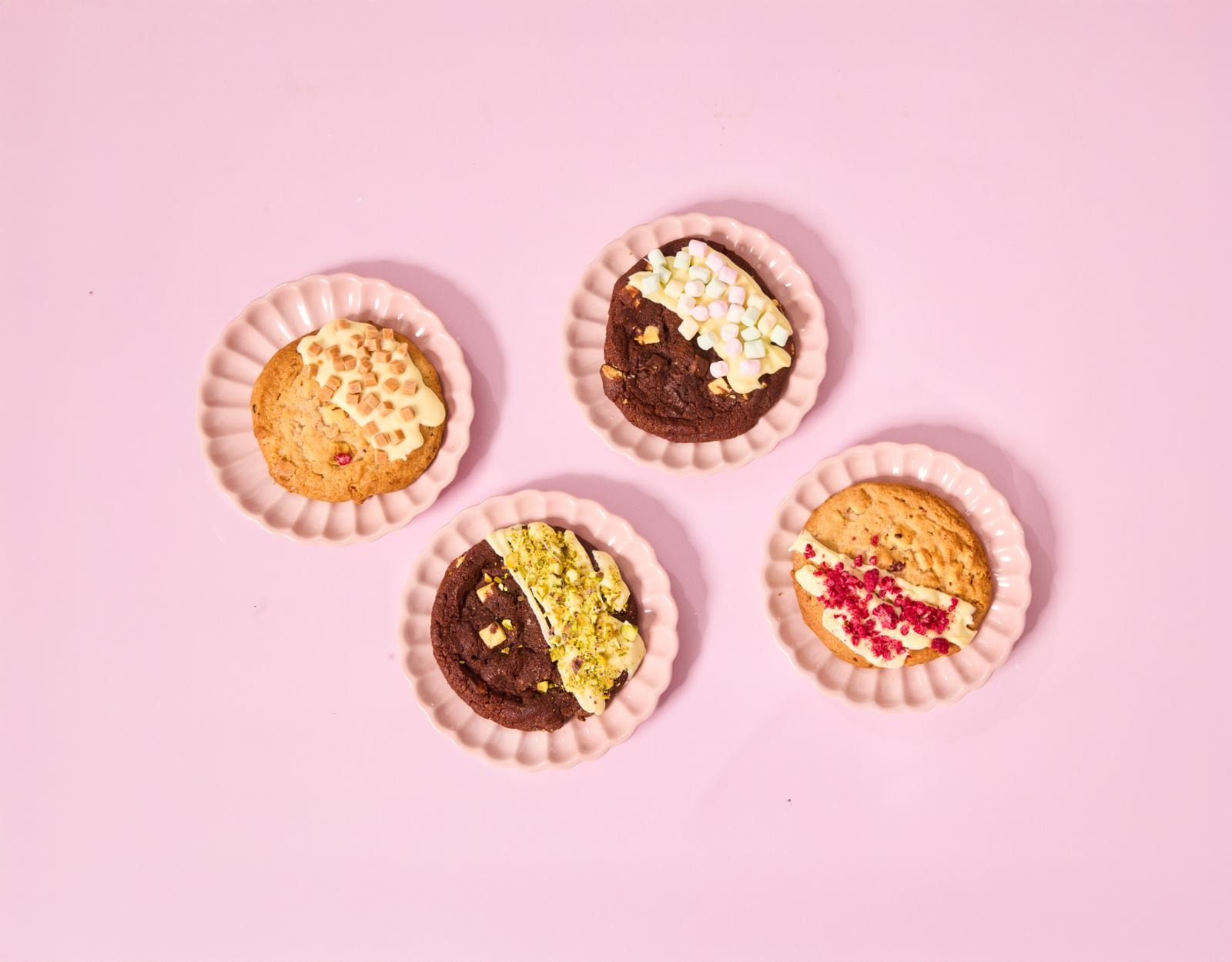 Neljä tuunattua cookieta vaaleanpunaisella taustalla
