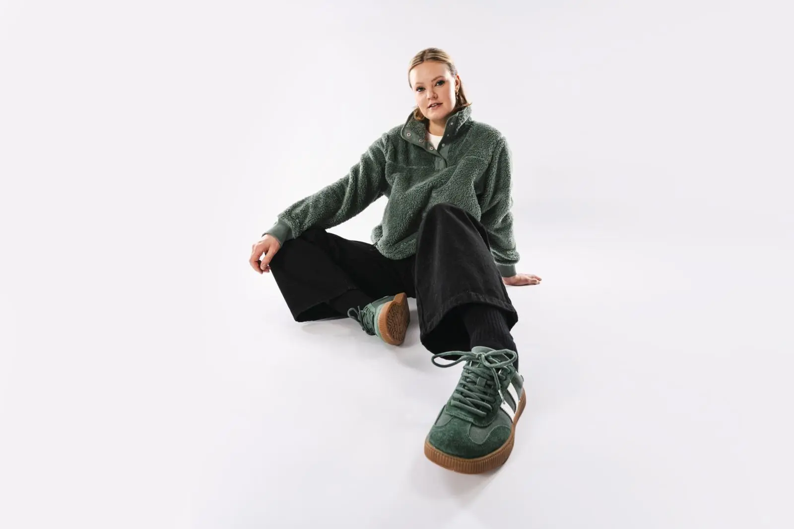 Mallin päällä vihreä paita, mustat farkut ja vihreät tennarit.