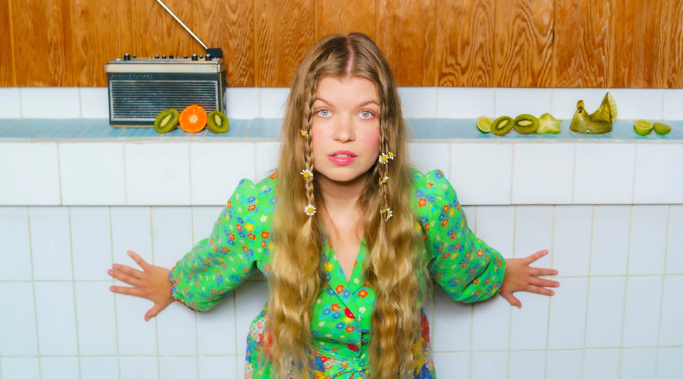 Henkilö valkoisesti laatoitetussa tilassa, jossa on puupaneeliseinä ja retro-radio.