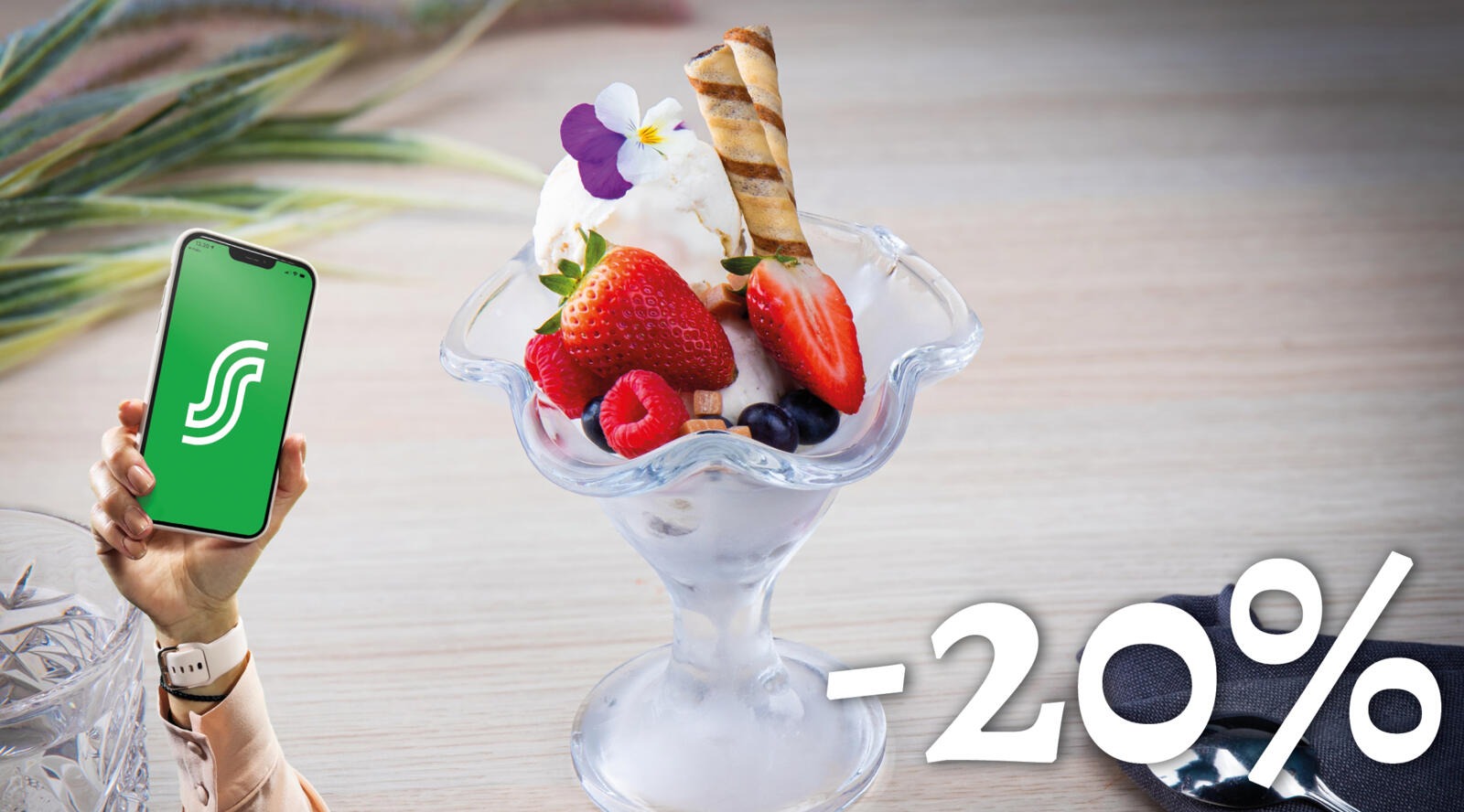 Glassportionen i glasskål, dekorerad med jordgubbar, hallon, blåbär, våffla och ätlig blomma.