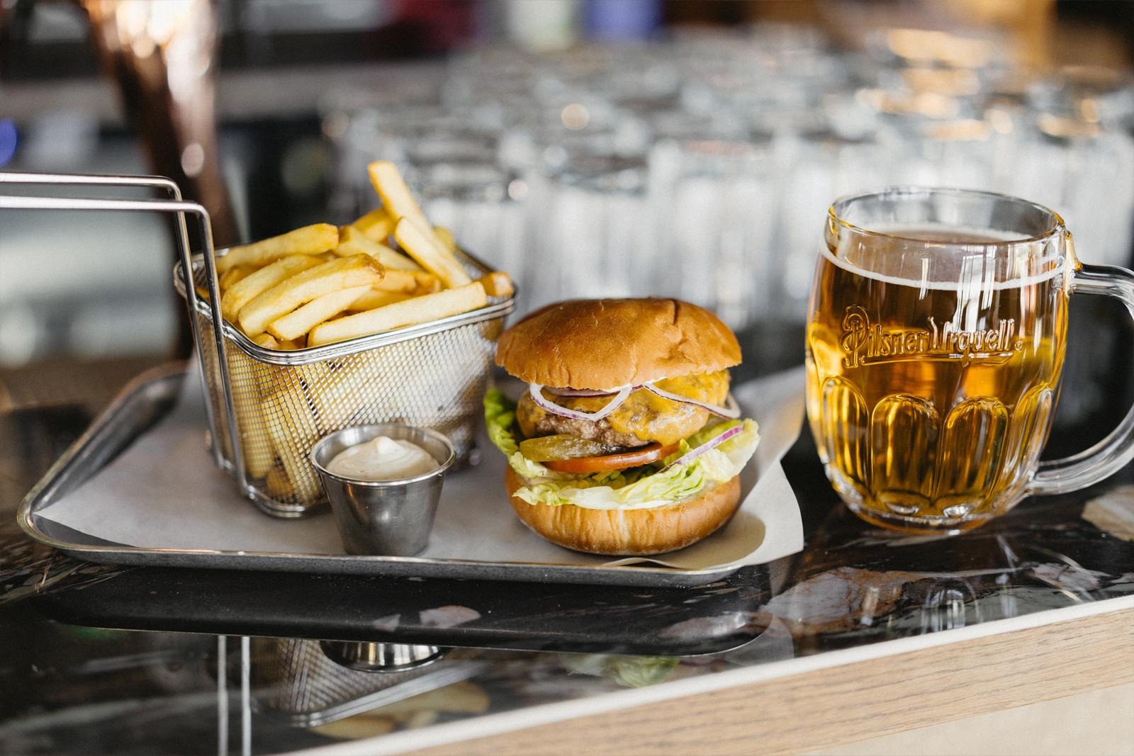 Ravintolan tiskillä tarjottimella ranskalaisia, dippi ja burgeri. Tiskillä myös oluttuoppi.