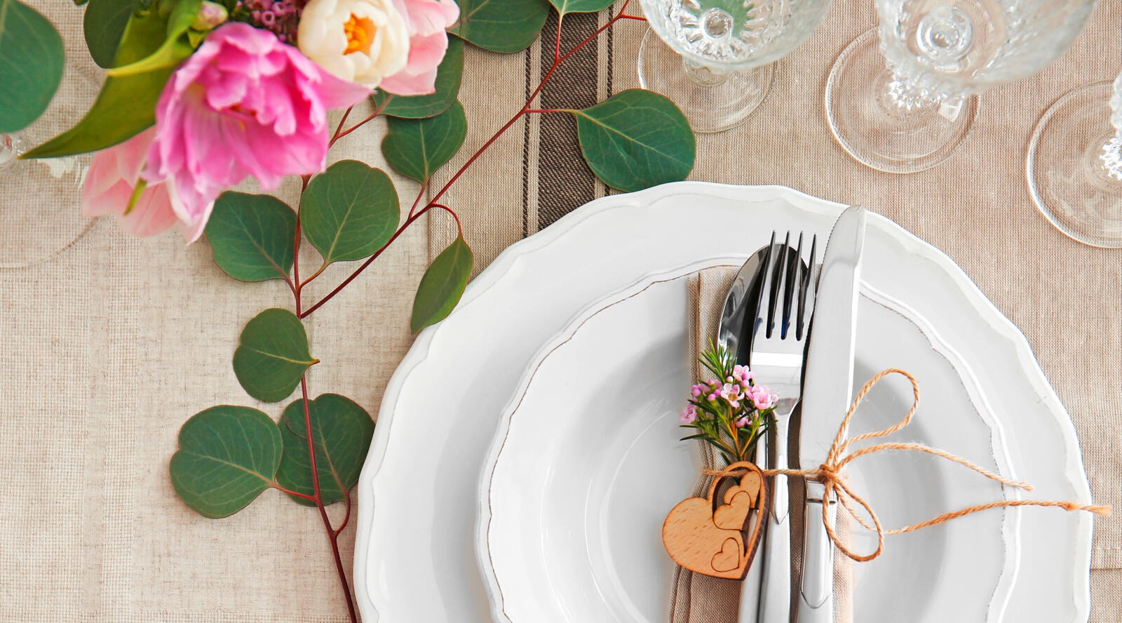 Puisella sydämellä koristellut aterimet ja lautanen pöydällä, jossa on kukkia.