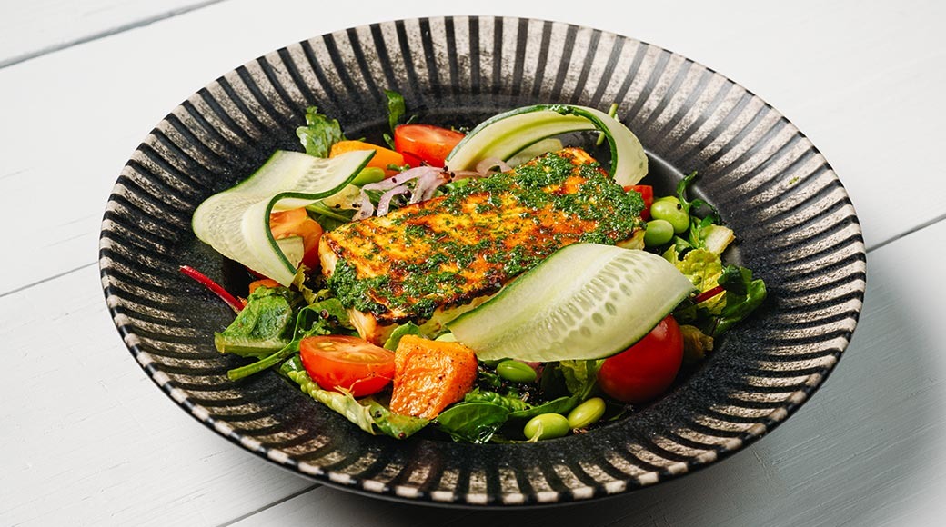 Tume triibuline kauss grillitud juustu ürdikastme, salatilehtede, kurgilintide, tomatite, edamame ubade ja kõrvitsaga.