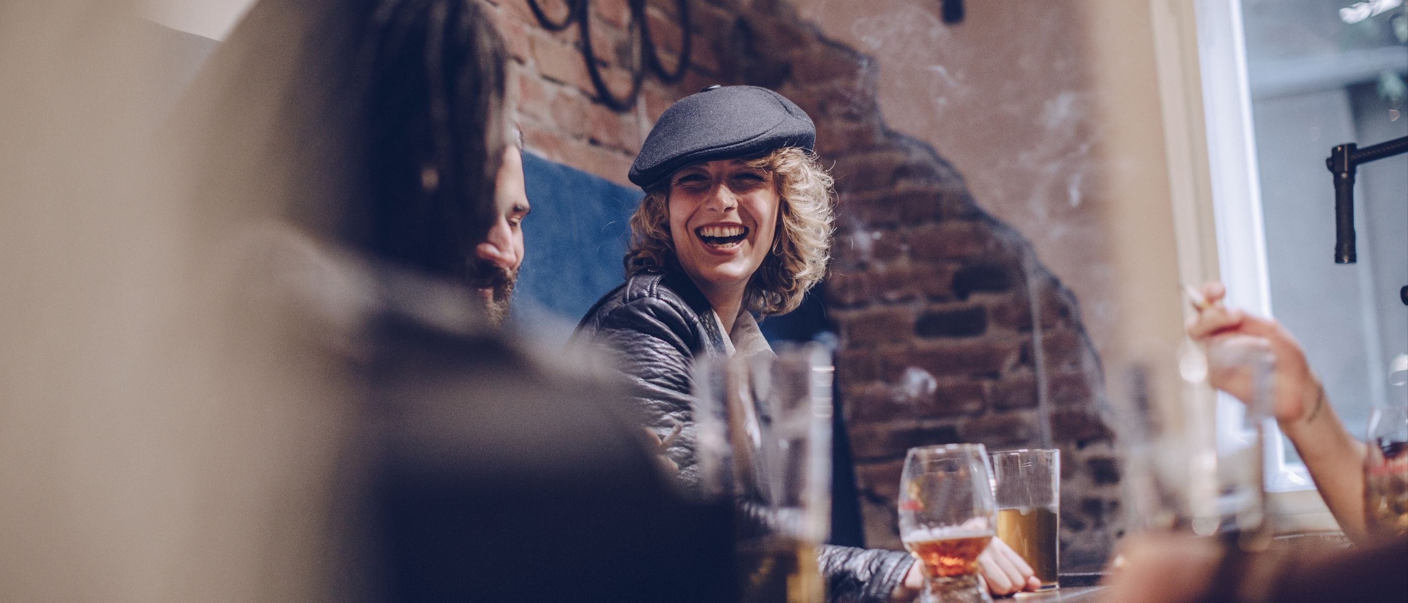 Ett glatt möte på restaurang med tegelvägg i bakgrunden. Vinglas och drycker på bordet.
