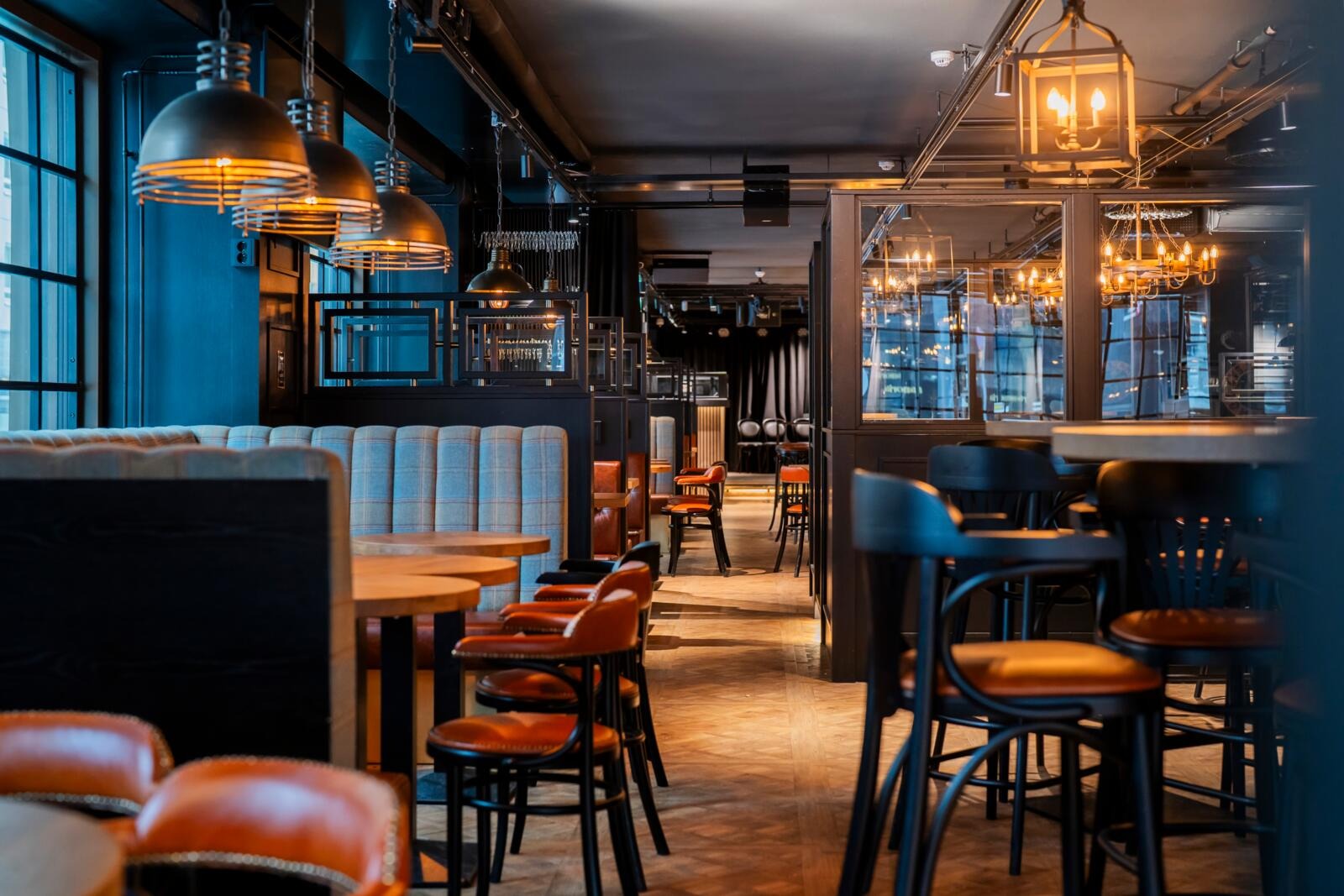 Tunnelmallinen ravintola sinisillä seinillä, tyylikkäillä riippuvalaisimilla, puulattia ja erilaisia istumaryhmiä muhkeilla sohvilla ja puisilla tuoleilla.