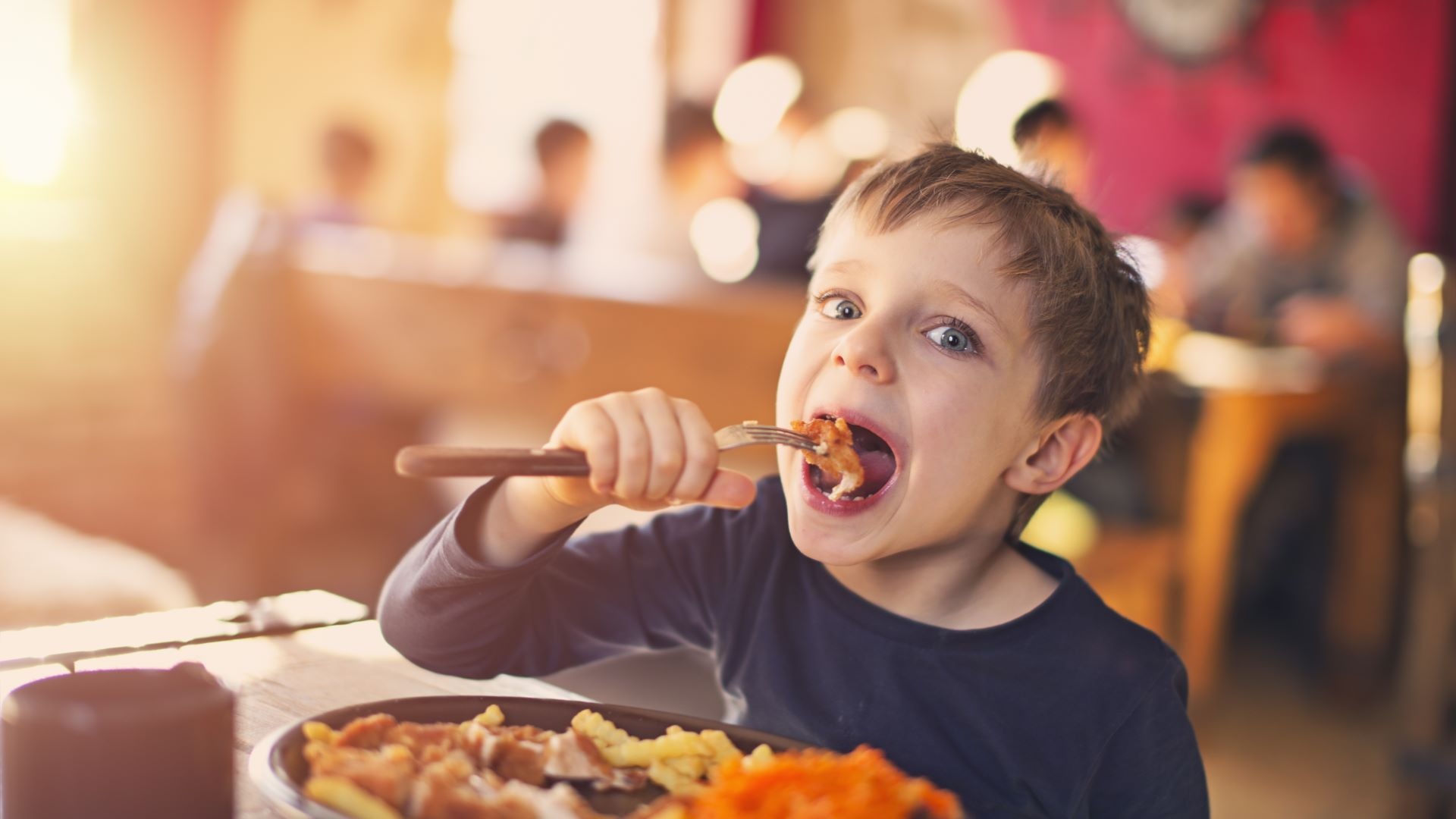 Lapsi syömässä innostuneena ravintolassa.
