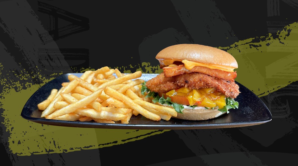Burger meal on a black plate: breaded patty, halloum cheese and lettuce in a bun, served with French fries.