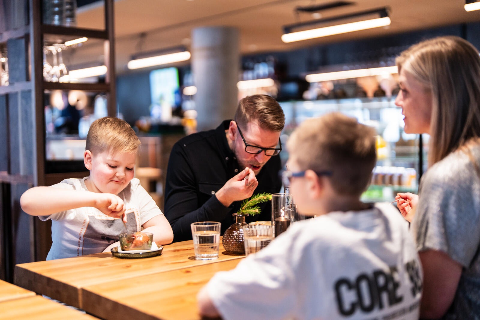 Family dining at a restaurant table in a spacious and well-lit interior.