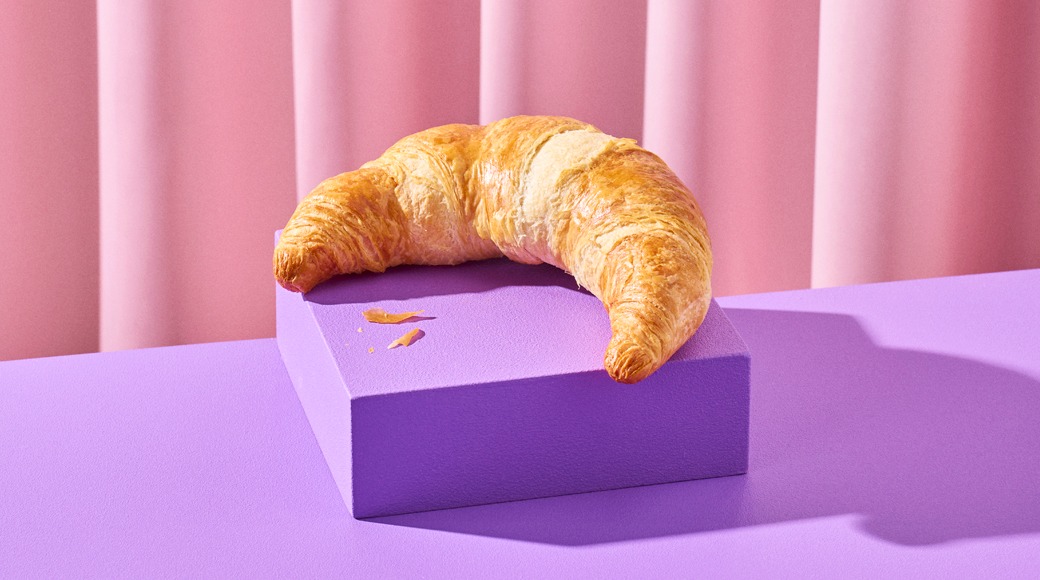 Voisarvi lepää violetin korokkeen päällä violetilla pinnalla, taustalla vaaleanpunainen laskostettu verho.