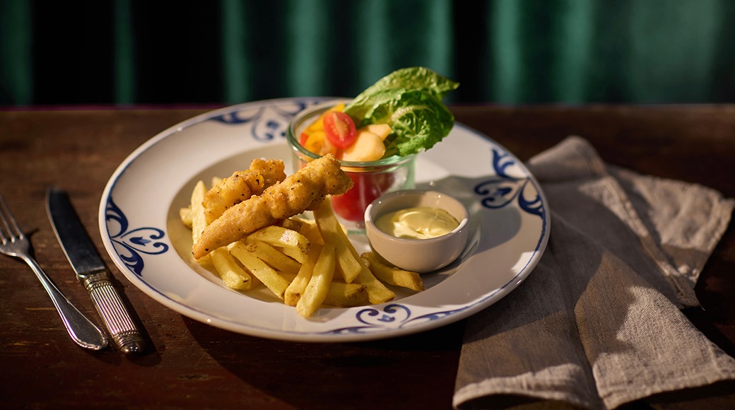 Annos kanapaloja ja ranskalaisia perunoita, lautasella myös salaattia pienessä kulhossa ja kastiketta toisessa kulhossa.