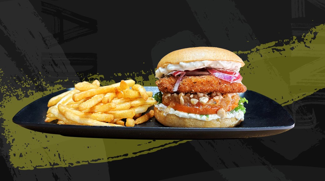 Burger meal on a black plate: crispy chicken fillet with lettuce, tomato, and onion in a bun, served with french fries.