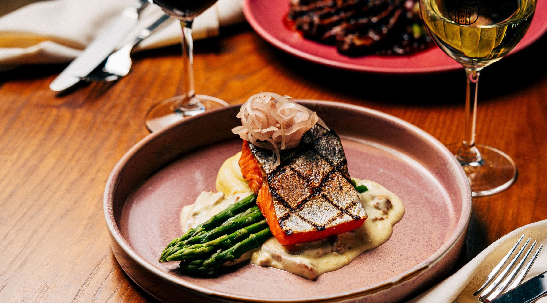 Gourmet-fiskrätt med drycker på träbord.