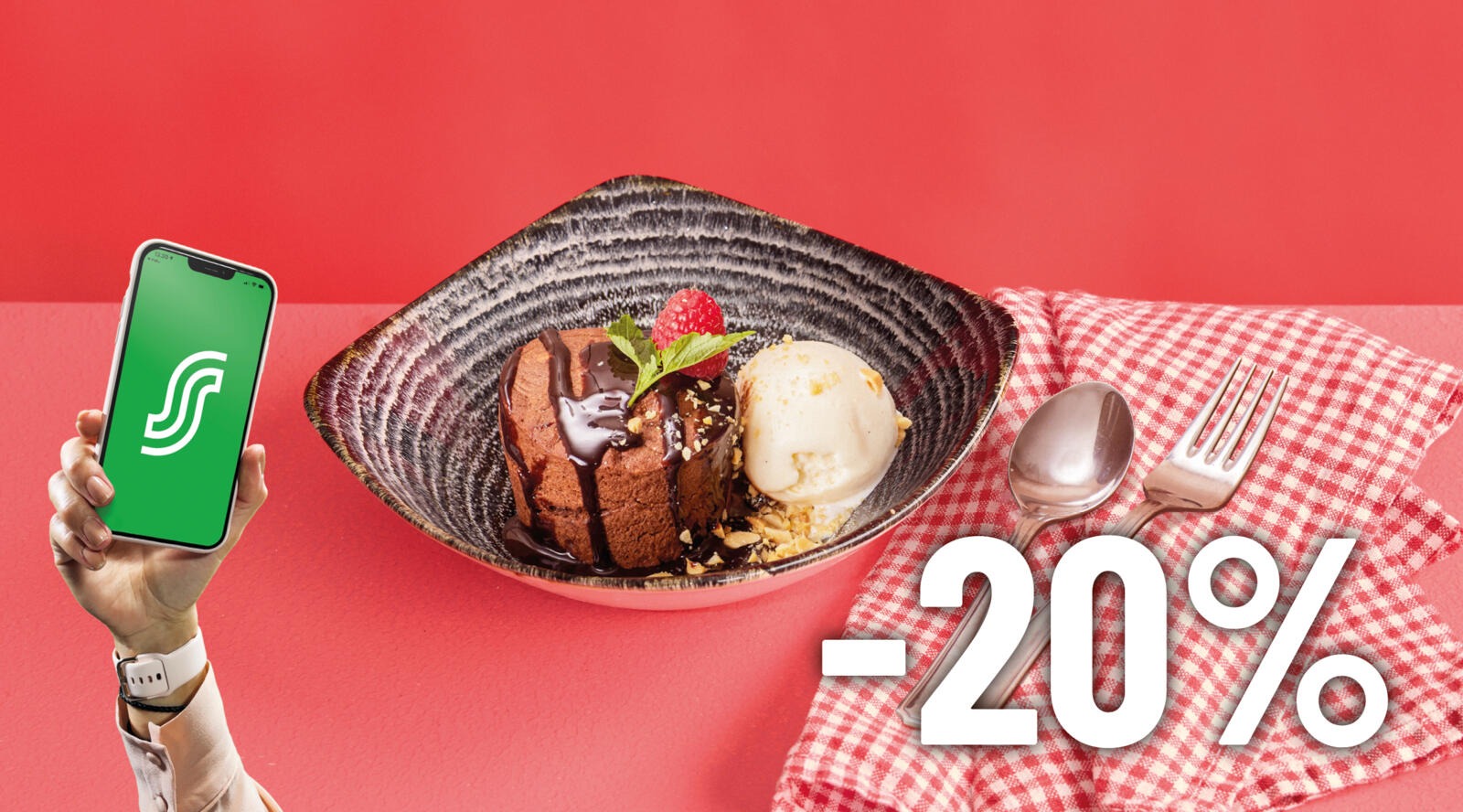 Hand som håller smartphone med grön applikation. Framför en desserttallrik med chokladkaka, vaniljglass och jordgubbe. Bestick på rutigt tyg.