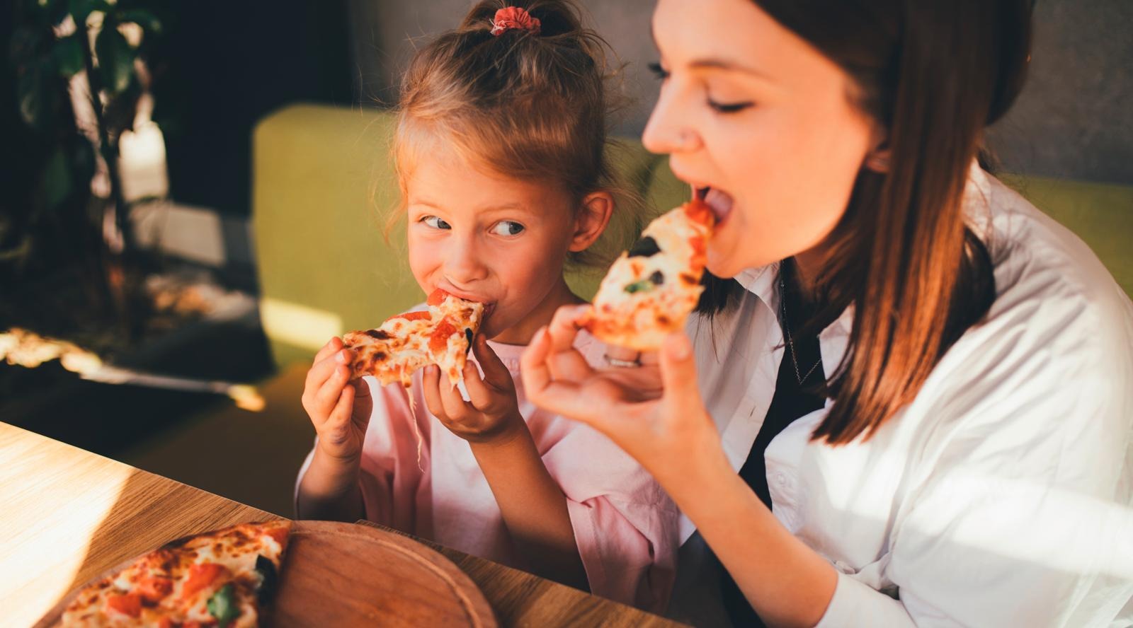 Äiti ja lapsi syömässä pizzaa