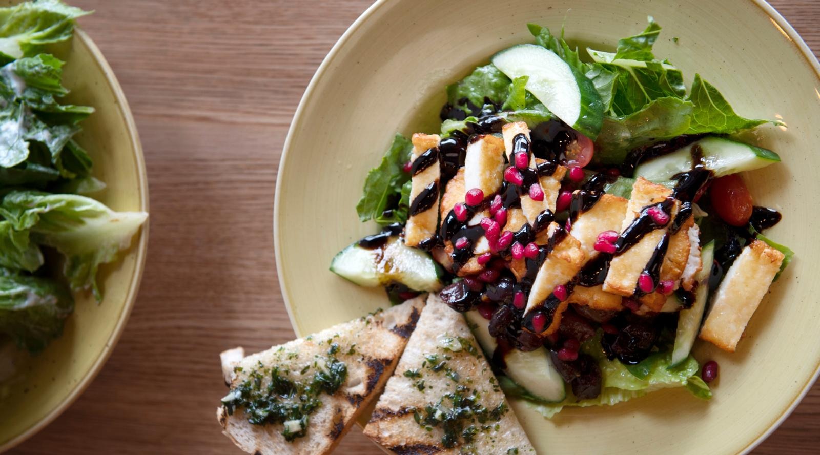 Lautasella kastikkeella koristeltua tofusalaattia ja valkosipulileipäpaloja.