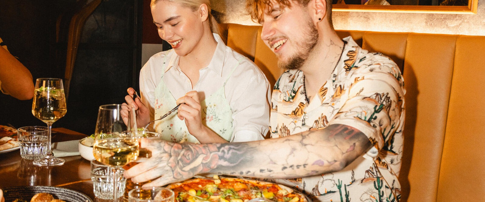 Två personer sitter vid ett restaurangbord och njuter av en måltid tillsammans.