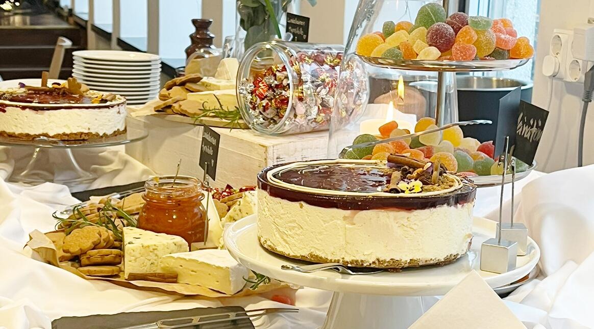 Festbord med tårtor på piedestaler, ostbricka, godisbehållare och färgglada gelégodisar.