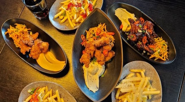 Pöydällä valikoima Tsikenin kana-annoksia mm. Crispy Chicken, Wings sekä ranskalaisia.