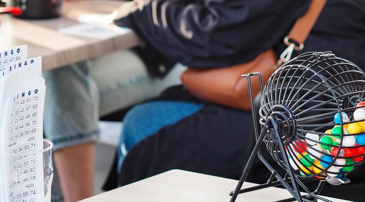Bingo laud numbrikaartidega ja metallist bingo pall täis värvilisi numbritega kuule.