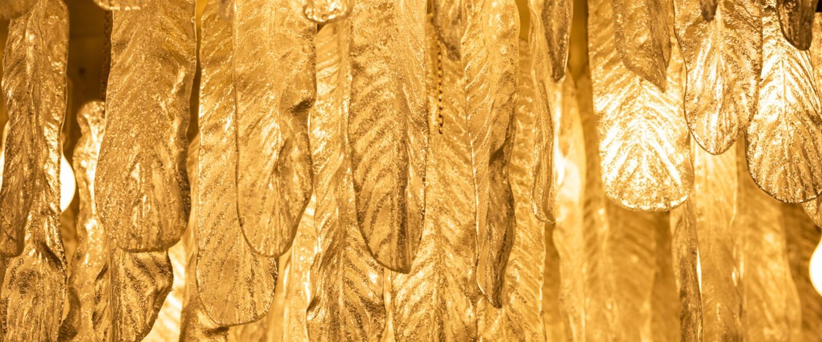 Närbild på gyllene bladdekorationer eller smycken som bildar en glittrande, lövmönstrad yta.