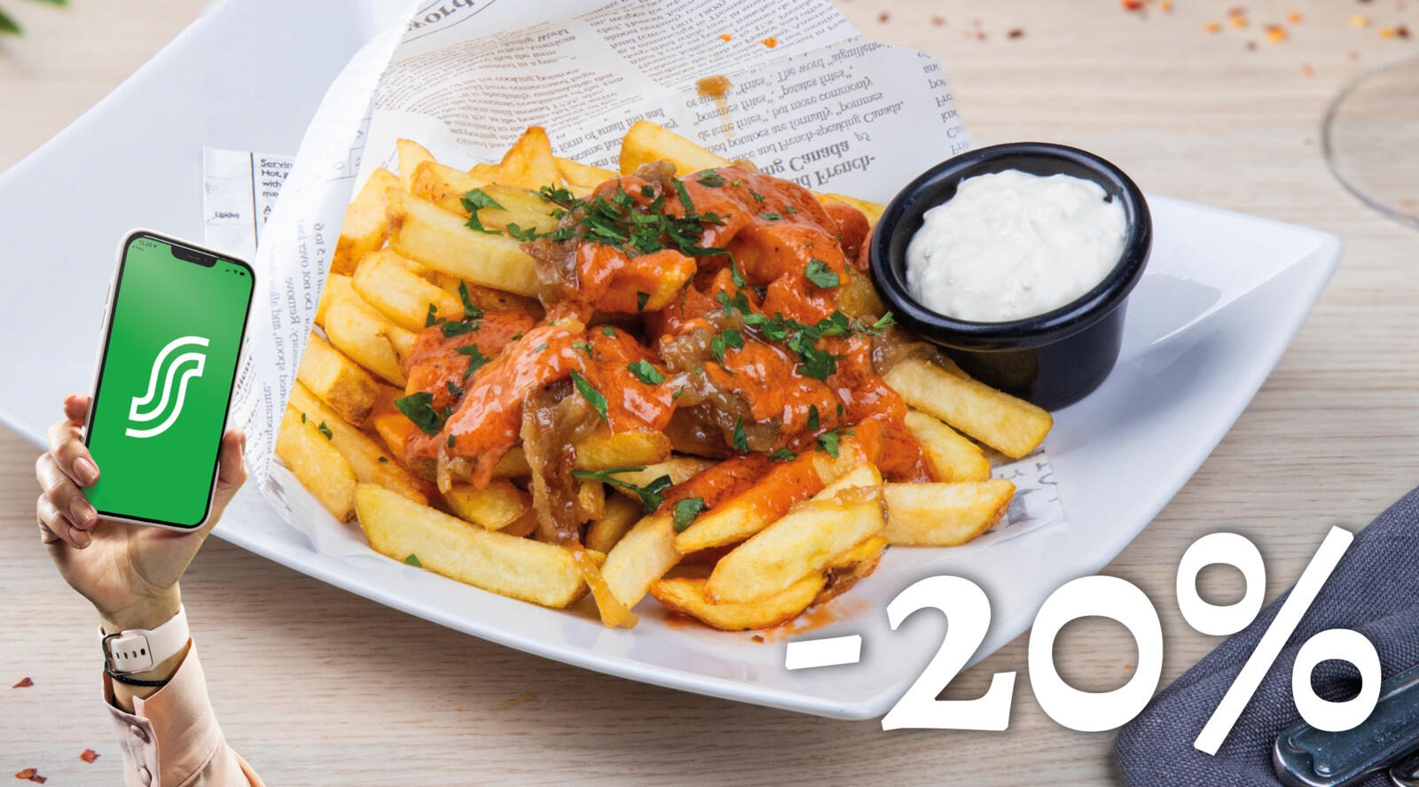 Tallrik med pommes frites toppade med paprikasås och vit dipp, serverad på en vit kantad tallrik på träbord.