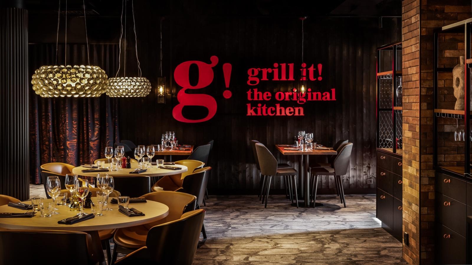 Punainen Grill it! -logo seinällä on keskeinen osa sisustusta, tuoden esiin ravintolan brändin ja tunnelman.
