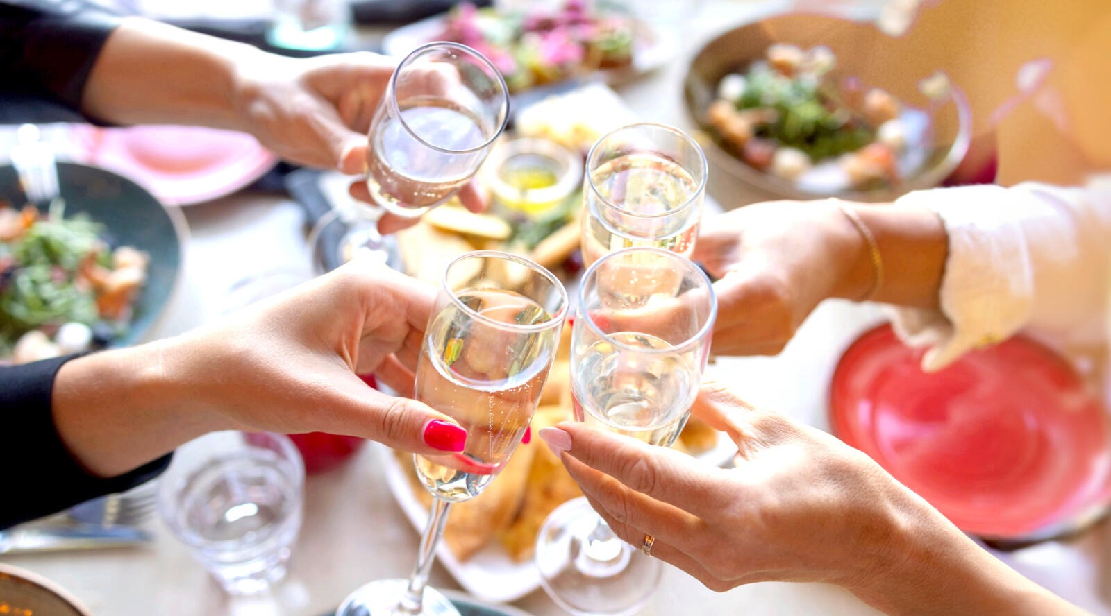 Neljä henkilöä kippistelevät katetun pöydän päällä.