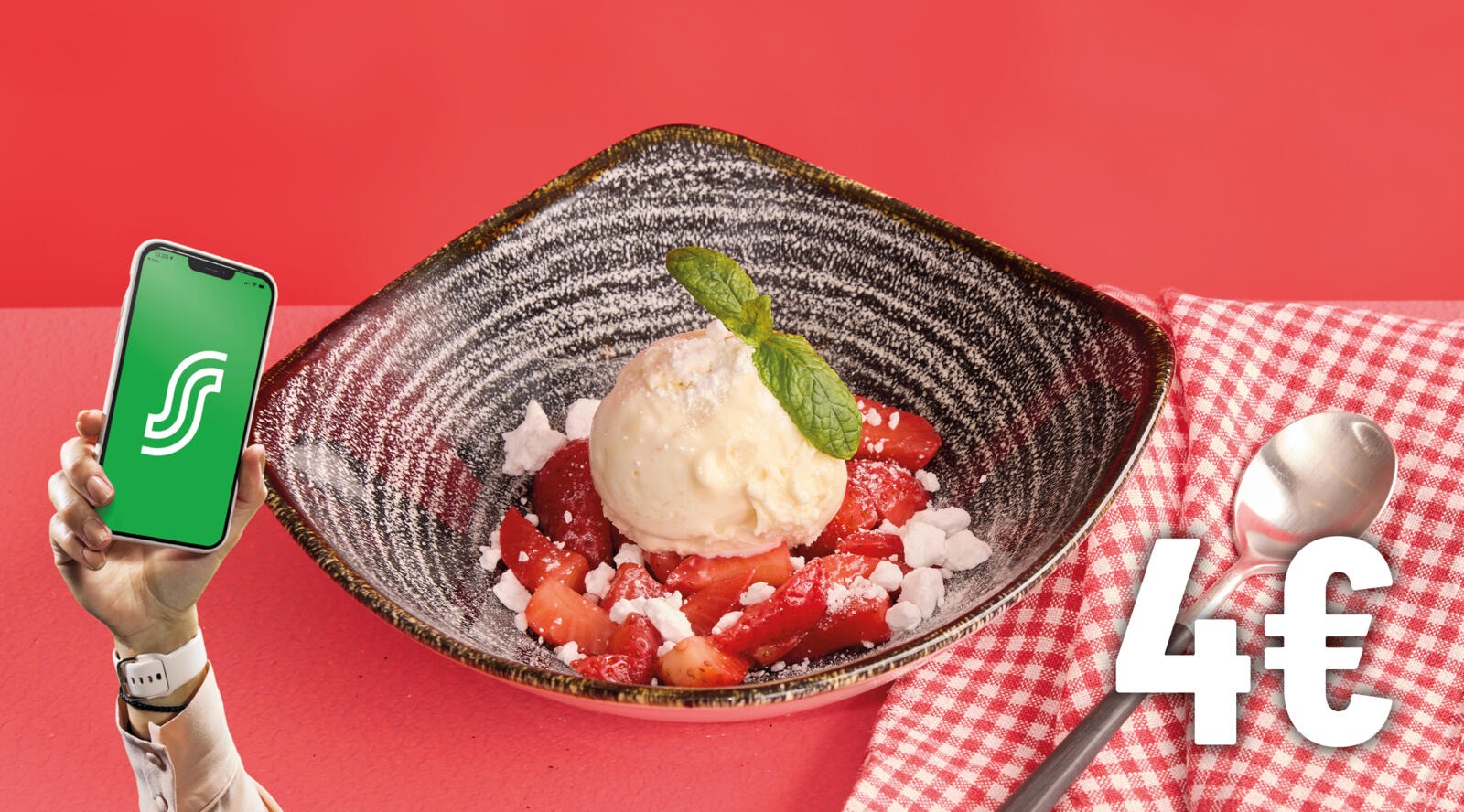 Hand holding a phone next to a dessert plate with vanilla ice cream, strawberries and a mint leaf.