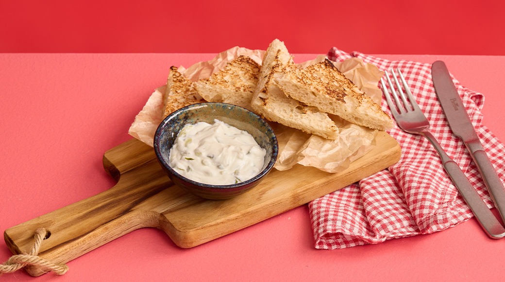 Puisella tarjoilulaudalla paahdettua leipää ja kulhollinen dip-kastiketta.