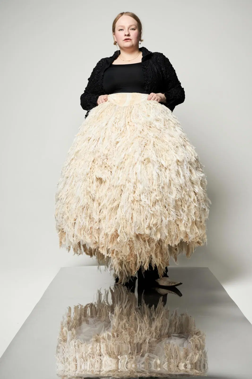 Enni Lähderinne pitää edessään suunnittelemaansa massiivista luonnonvalkoista hametta.