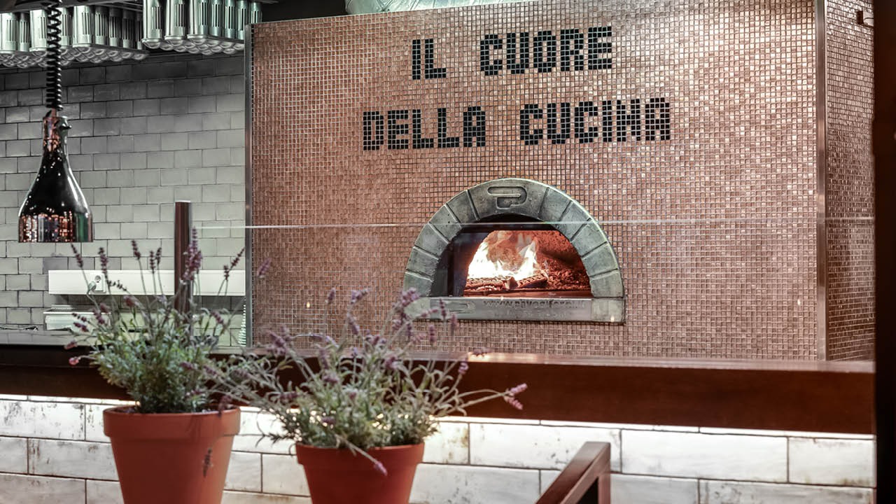 Perinteinen italialainen puulämmitteinen pizzauuni Oulun Rossossa, liekit näkyvät uunin sisällä.