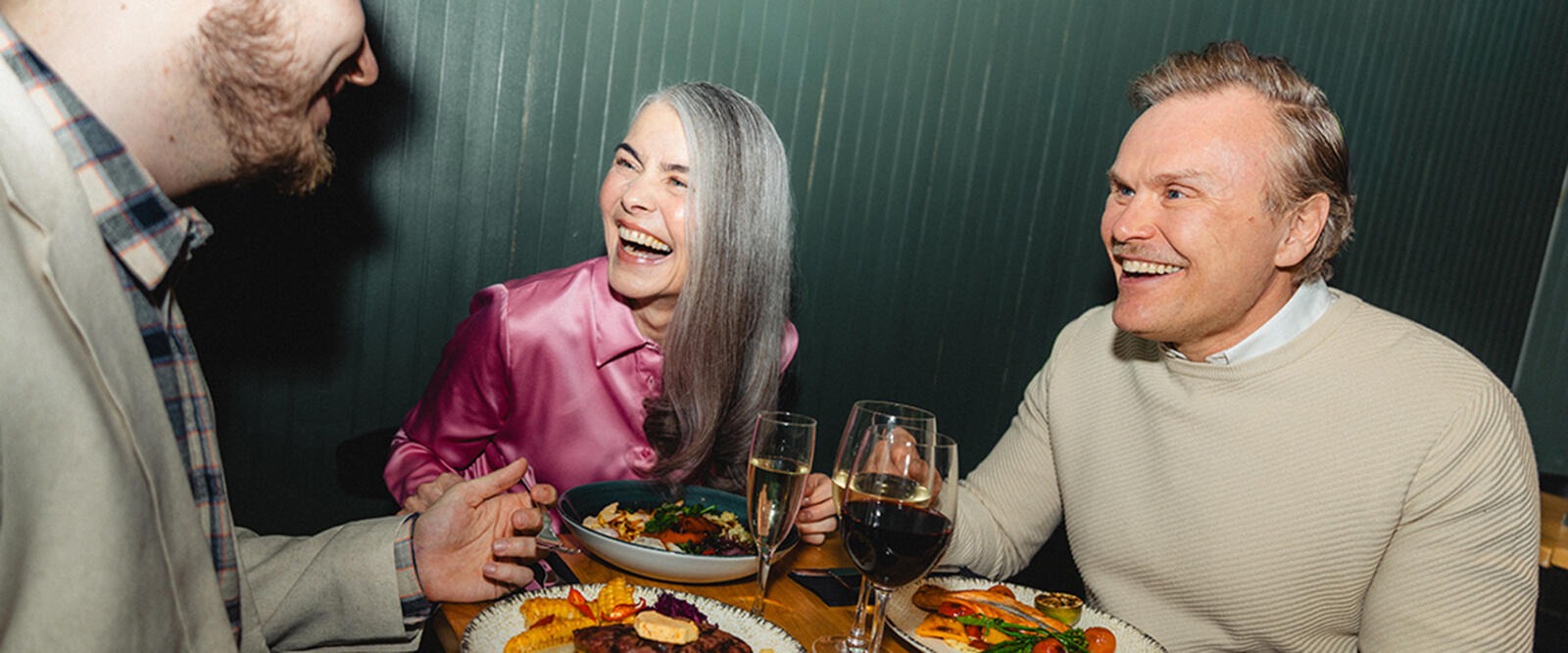 Människor njuter av en måltid och drycker i restaurangens polstrade bordsavdelning.