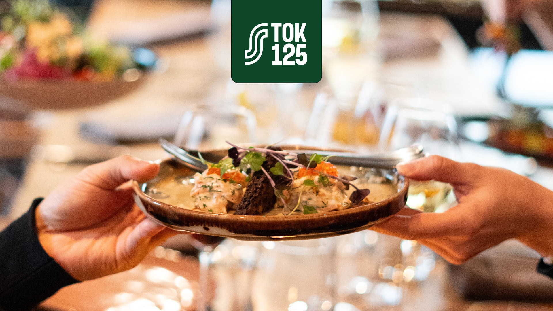 Käed hoiavad dekoratiivset taldrikut lihapallide ja kastmega, kaunistatud ürtide ja kaaviariga.