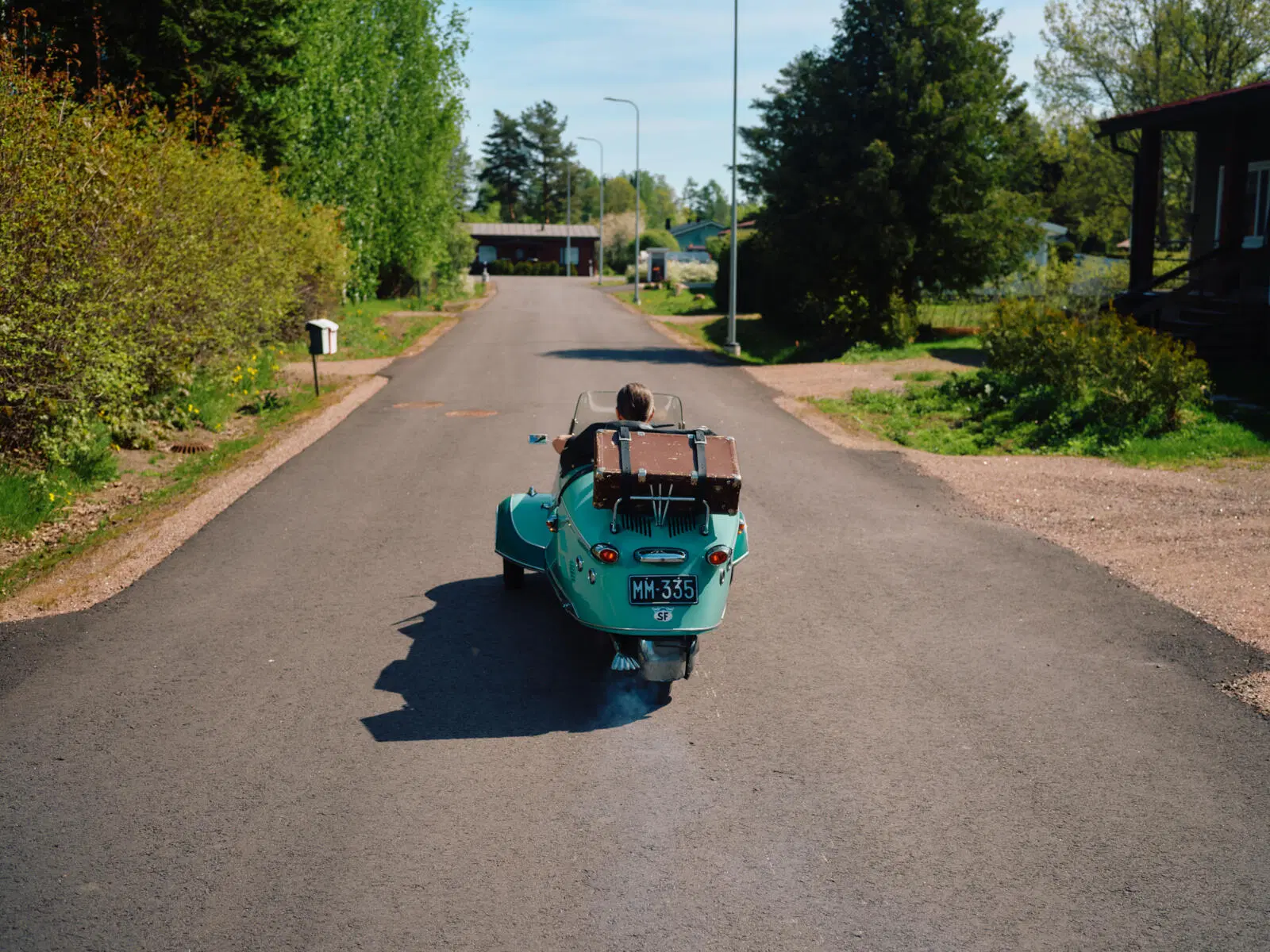 Turkoosi Messerschmitt kuvattuna takaapäin. Auton kyydissä on vanha matkalaukku.