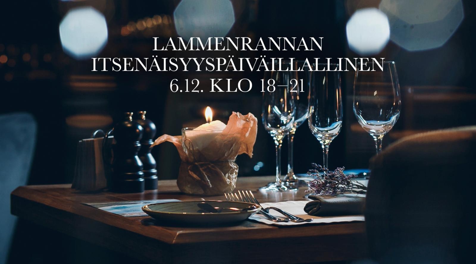 Elegantly set restaurant table with candle, wine glasses and cutlery in dimly lit ambiance.