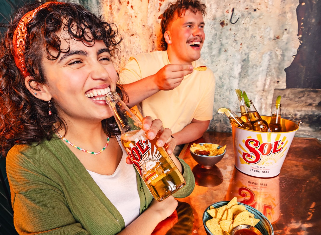 Kaks inimest naudivad jooke ja nachosid. Laual on Soli õllekahur ja nachokausid.