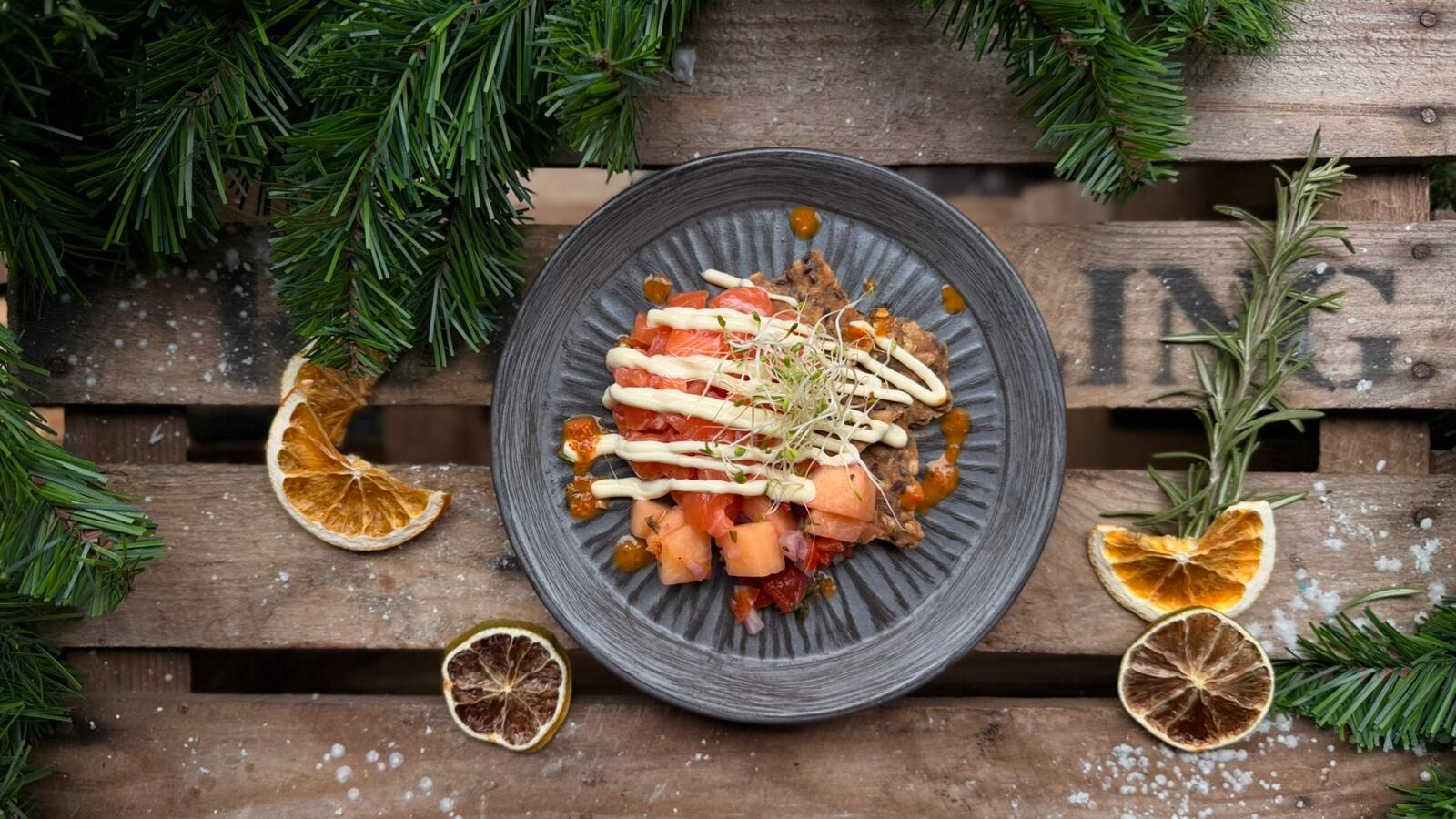 Gourmet-lohiannos rustiikilla lautaslautasella, koristeltu kuivatuilla sitrushedelmäsiivillä ja havunoksilla.