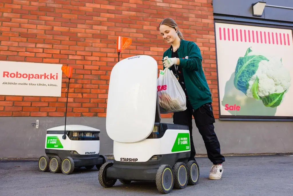 Pirkanmaan Osuuskaupan työntekijä täyttää kuljetusrobottia Salen edessä. 