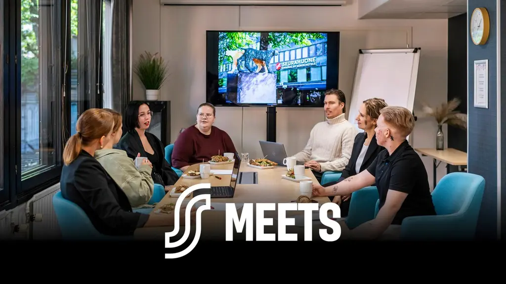 Seurahuoneen kokoustilassa ihmisiä.