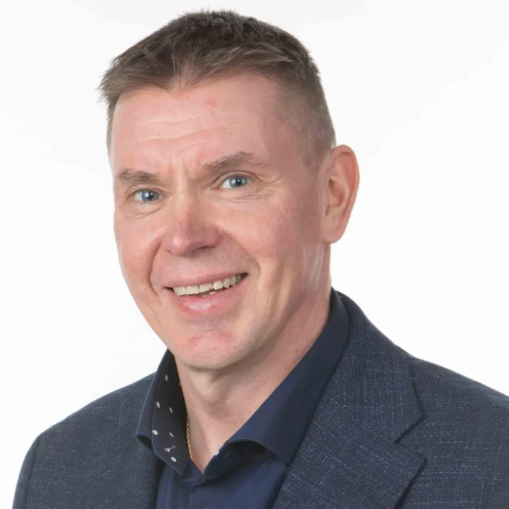 Mies katsoo kameraan hymyillen