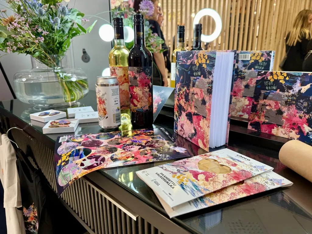 Erilaisia tuotteita, kuten sulkaa, tarrat, pullo, korvakorut ja tölkki, pöydällä