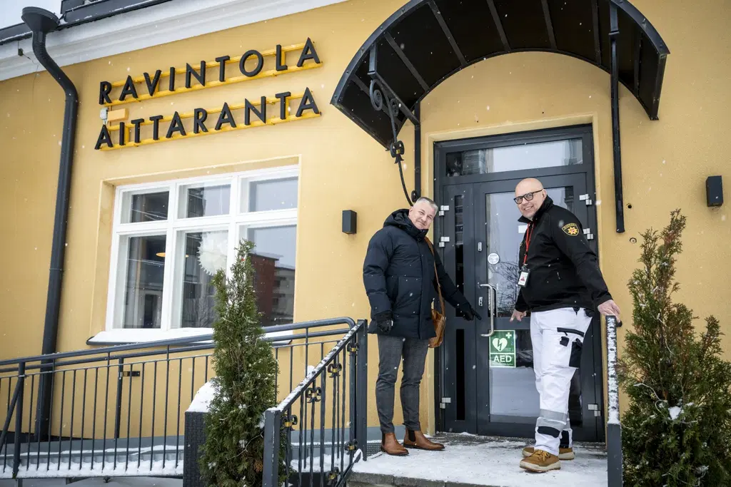 PKO:n työsuojelupäällikkö Jari Jurvanen (vas.) ja Pohjois-Karjalan pelastuslaitoksen ensihoitopäällikkö Kari Törrönen näyttävät miltä defibrillaattori näyttää mikä merkki kertoo, että rakennuksessa on sydäniskuri.