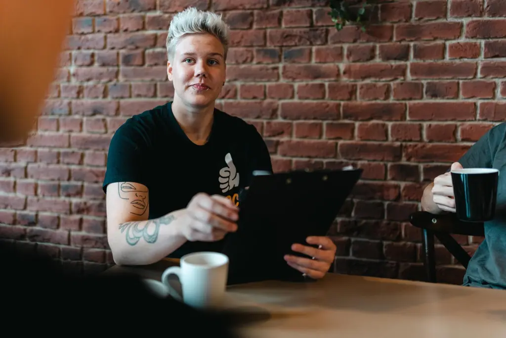 ABC-työntekijä istuu pöydän ääressä ja katsoo vastapäätä istuvaa. Pöydässä on myös kaksi muuta henkilöä, joiden kasvoja ei näy.