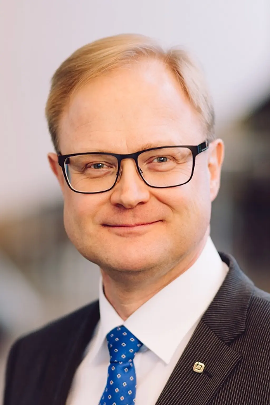 Mies katsoo kameraan hymyillen