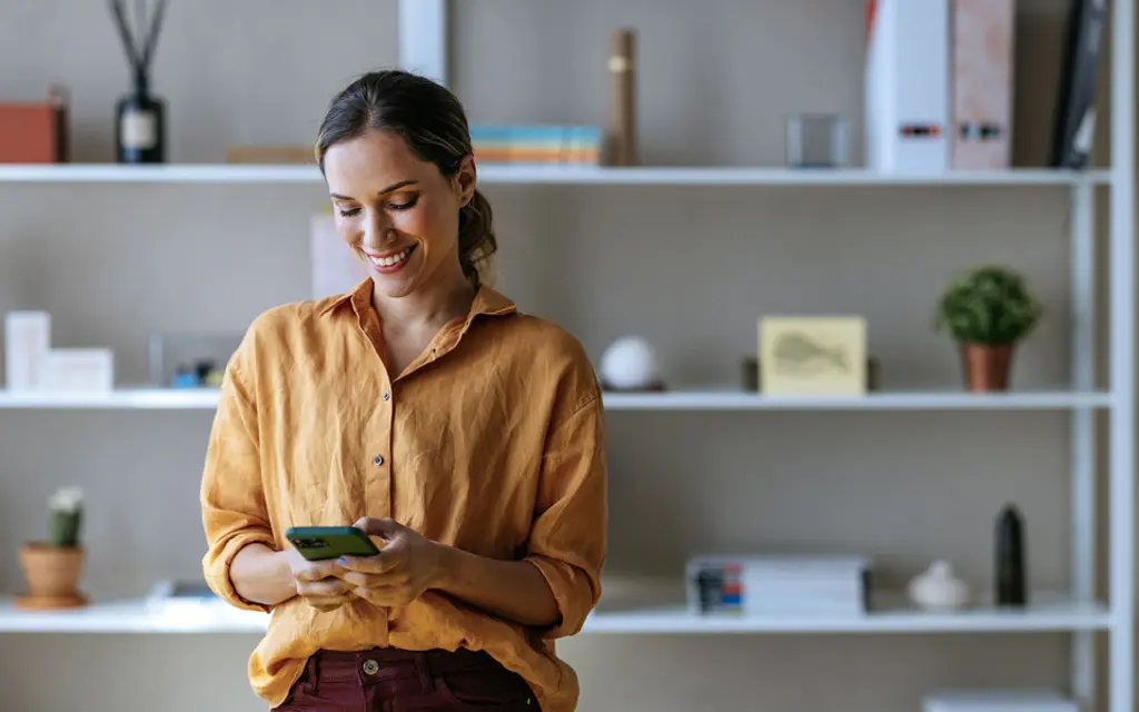 Nainen katsoo älypuhelinta ja hymyilee